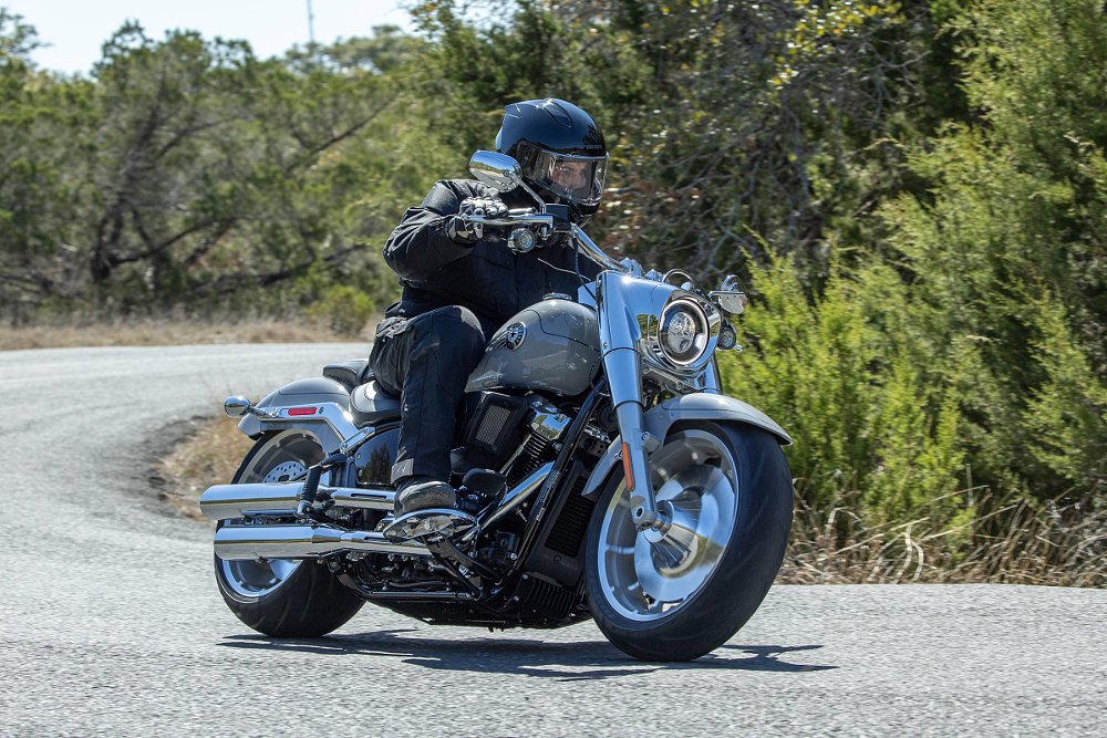 the author riding a silver Harley-Davidson Fat Boy through a curve