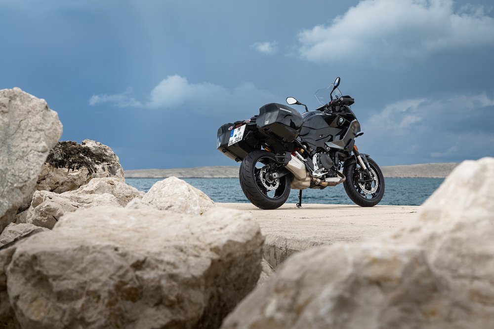 motorcycle parked by white rocks and a blue lake